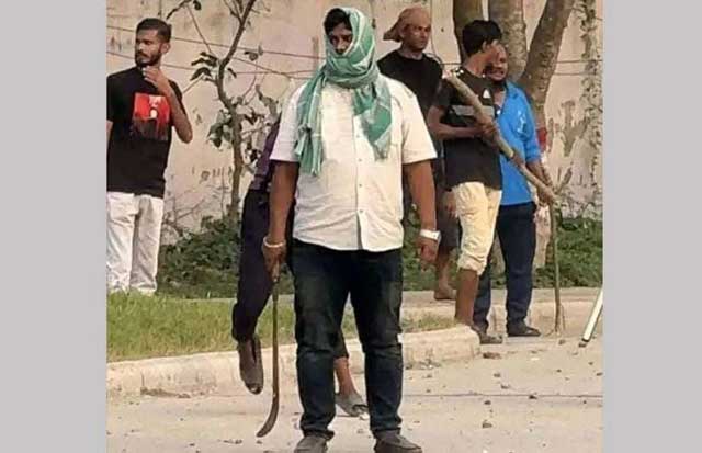 রামদা হাতে দাঁড়িয়ে থাকা যুবদল নেতা মাহবুবুর রহমান। ছবি: সংগৃহীত